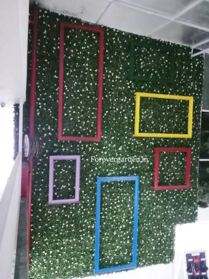 A fun and interactive selfie wall made from a green hedge panel and decorated with colorful empty frames.