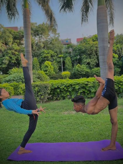 A beautiful display of mutual balance. This partner leg-balance pose requires both individuals to act as a counterbalance for each other, creating a single, stable shape.