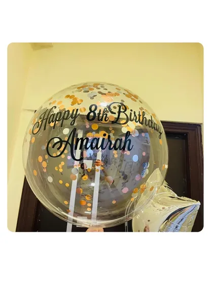 A close-up of a personalized bubble balloon for an 8th birthday. We can add any name and message, and we love how the rose gold confetti adds a fun, sparkly touch.