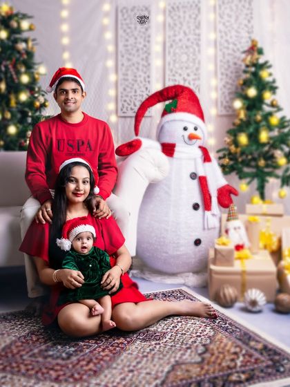 A classic family pose in festive red and green. The baby's happy smile is the centerpiece of this lovely Christmas portrait.