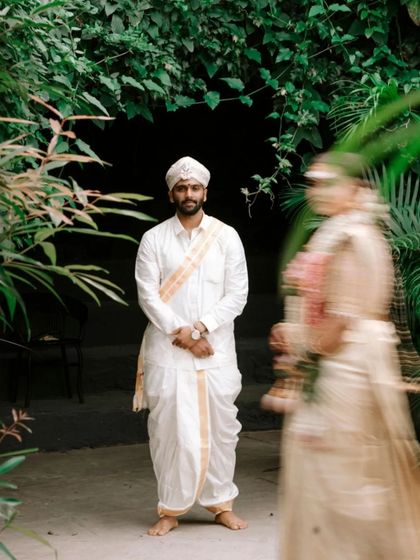 A creative first look photo, with the groom in focus and the bride approaching with a beautiful motion blur. This artistic shot builds anticipation and tells a story.