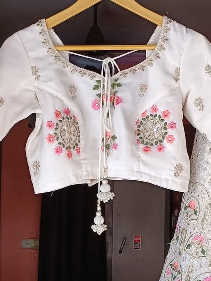 The matching blouse for the white floral lehenga, featuring delicate embroidery and a stylish tie-back.