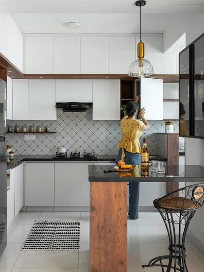 This shot shows the kitchen and bar counter in use, highlighting its functionality as both a prep area and a social spot. The design features diamond-patterned tiles and mixed material cabinetry.
