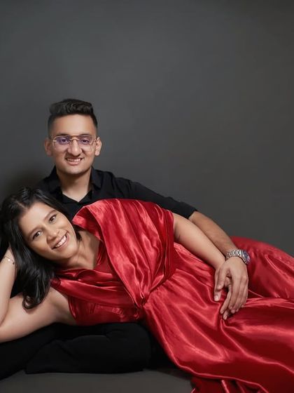 A cozy and intimate studio maternity shot. The rich red satin of our 'Scarlet' wrap gown drapes beautifully for this relaxed, floor-seated pose.