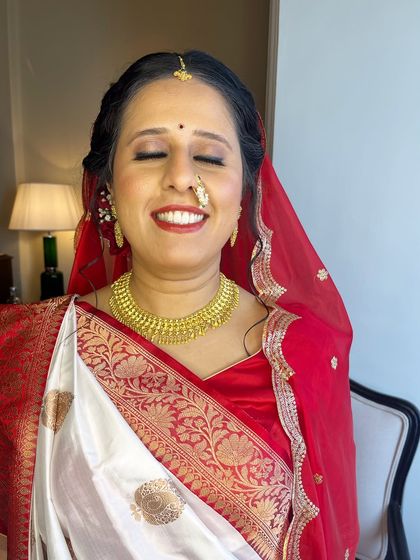 A close-up of the Gujarati bridal makeup. The look is soft and glowing, with a classic red lip and subtle shimmer on the eyes.