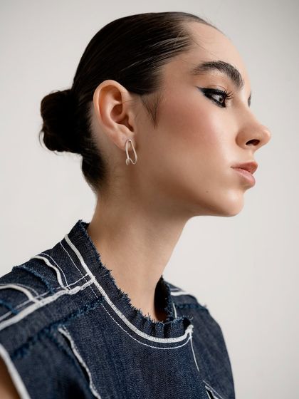 A close-up from a womenswear shoot that also serves as a great jewelry shot. The focus is on the simple, elegant hoop earring, complemented by the model's strong profile and dramatic eye makeup.