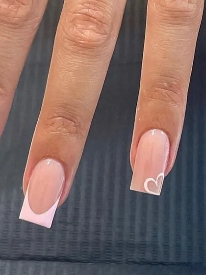 A light pink French manicure on square nails, with a single accent nail featuring a small, hand-drawn white heart.