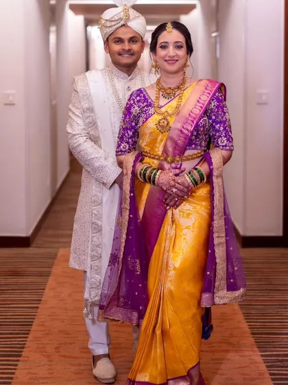 The happy couple. The bride's yellow and purple Kanjeevaram is draped in a traditional style with a contrasting dupatta, celebrating the union of two cultures.
