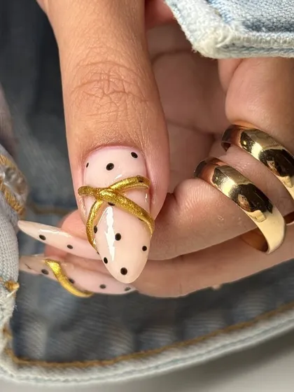 A detailed shot of the sculpted gold 'X' accent on a polka-dotted nail, demonstrating the 3D artistry we can achieve.