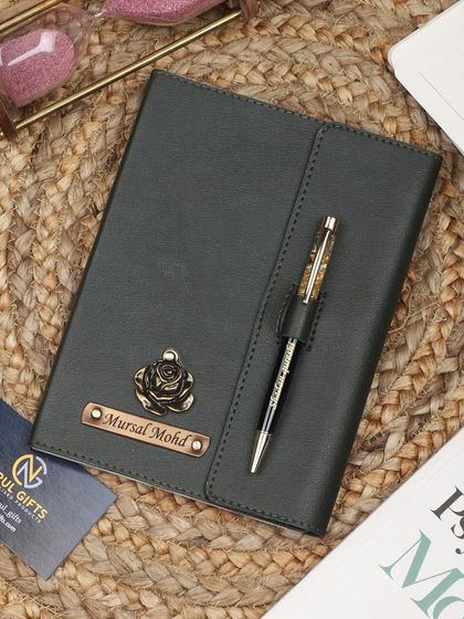 A green leather diary and pen set with a rose charm.