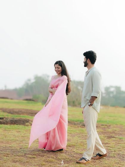 A candid moment of her looking back at him as they walk through the field. The flowing saree adds a touch of elegance and movement.