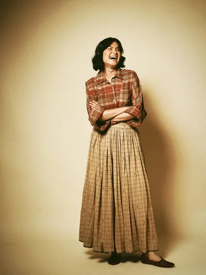 A full-length studio portrait for House of Wandering Silk, capturing a moment of laughter. It shows that fashion can be joyful and relaxed.