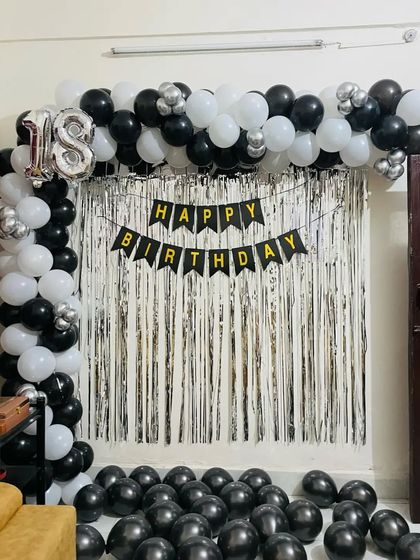 A simple and stylish half-arch for an 18th birthday, using a black and white theme with a silver shimmer curtain.