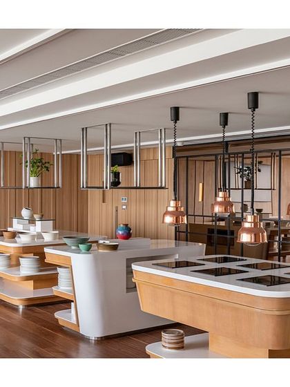 The main servery and buffet counter in the dining area of 'The Office with A View'. The design is clean and functional, with a mix of materials including Corian and wood laminate, and custom overhead shelving.