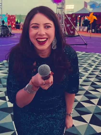 A fun, interactive pose with the microphone, inviting the audience to join in.