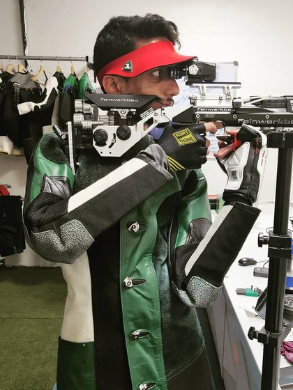 An athlete using a Feinwerkbau air rifle, demonstrating the advanced equipment our shooters train with. The specialized shooting jacket provides essential support for the torso and arms.