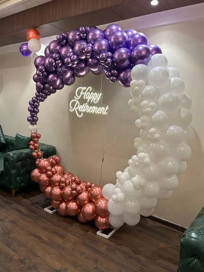 A stylish and colorful setup for a retirement party. The circular balloon arch uses a unique color combination of chrome purple, rose gold, and white, creating a modern and festive look to celebrate a new chapter in life.