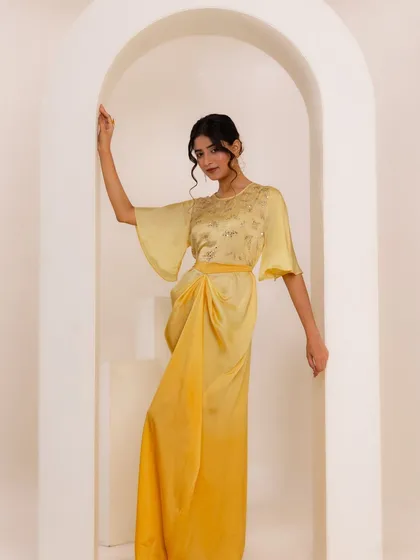 A beautiful shot from the same indo-western shoot. The model is wearing a draped yellow dress with bell sleeves, and the arched backdrop adds a touch of architectural elegance.