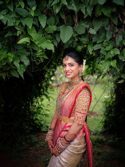 A classic portrait of the bride framed by lush greenery. The makeup is timeless and elegant, perfect for creating lasting memories.