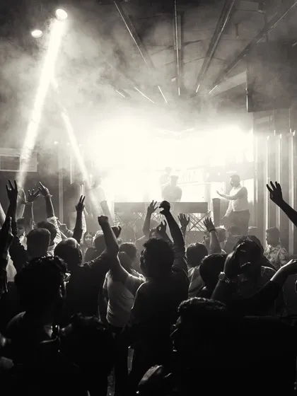 This black and white shot captures the raw energy of the dance floor. The combination of smoke, spotlights, and a crowd with their hands up is the essence of a great club night.