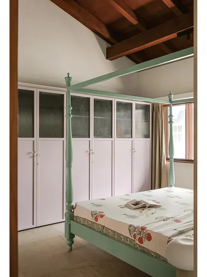 In this bedroom, a mint-green four-poster bed is paired with lilac-painted wardrobes. The contrast of colours, along with the traditional form of the bed and the simple lines of the cabinetry, creates a space that is both whimsical and contemporary.