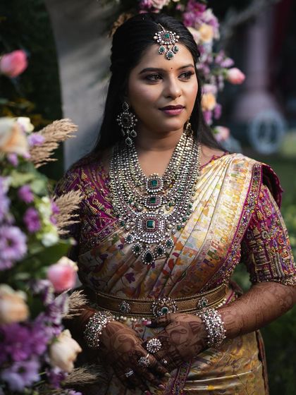 A portrait of the bride against a floral backdrop, looking like a queen in her magnificent attire.