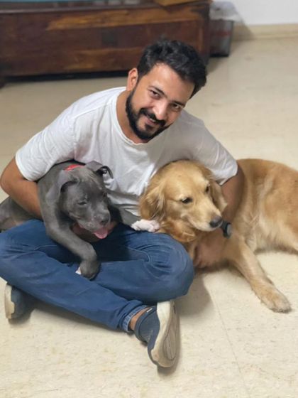 A happy pile of pups. Brutus as a puppy cuddling with his human friend and a Golden Retriever, showing the social and friendly atmosphere we cultivate.