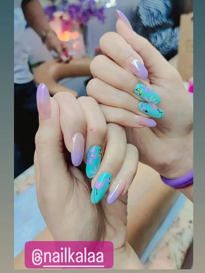 A creative and colorful set combining pastel purple nails with turquoise accent nails featuring abstract black line art.