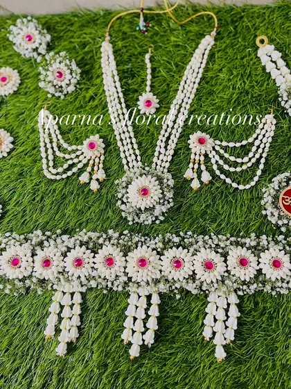 A full view of an intricate baby shower set. The kamarband is especially detailed, with multiple floral pendants made from fresh jasmine buds.