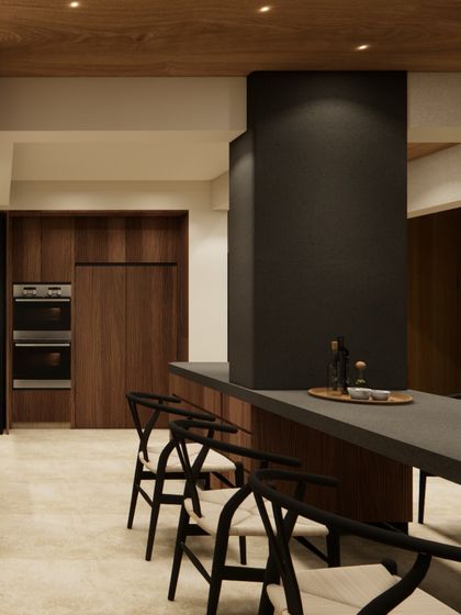 A view of the open-plan kitchen and dining area, where a dark monolithic column provides a grounding contrast to the warm wood cabinetry. This space is designed for gathering and sharing stories.