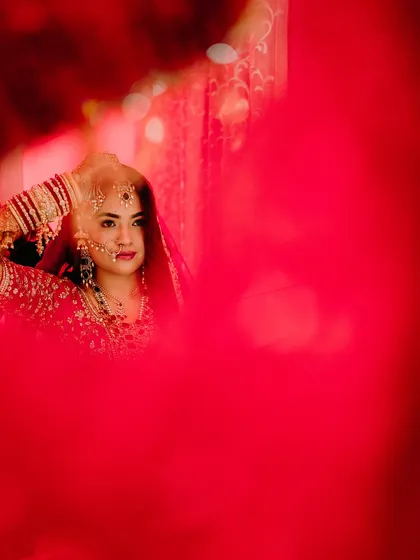 An artistic shot of the bride getting ready, seen through a vibrant red filter. This creative technique adds a layer of drama and passion to the portrait.