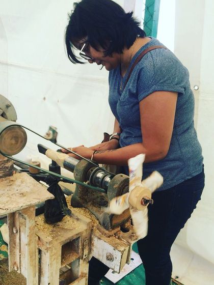 With intense focus, a participant learns to handle the chisel on the spinning lathe. This is the most crucial step in toy making, where the raw wood begins to take on a new form under the creator's touch.