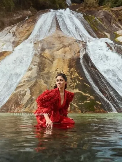An ethereal shot from our editorial collaboration with Femina Miss India in Arunachal Pradesh. The model's hair is styled to flow naturally, complementing the dramatic red gown and the powerful waterfall backdrop for a high-fashion, camera-ready look.