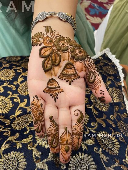 A stylish back-of-hand design with floral motifs and hanging jhumka elements. The patterns on the fingers complete this chic, jewellery-inspired look.