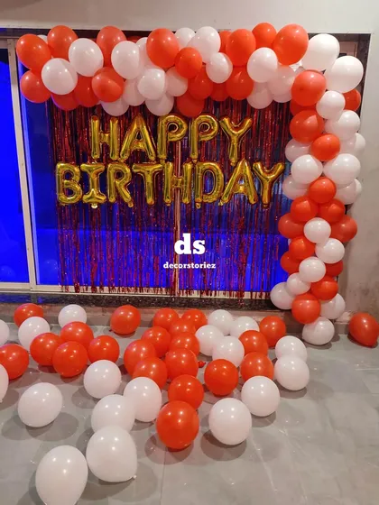 A bold and classic red and white balloon arch over a red shimmer curtain. The 'Happy Birthday' foil balloons in gold add a touch of contrast and celebration.