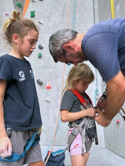 A father helps his kids get their harnesses fitted correctly. Safety is a team effort, and we guide families through every step.