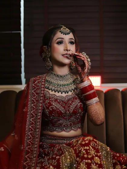 Here is a closer look at a stunning bridal client. The HD makeup features intricate eye work with a subtle cut crease, a defined contour, and a neutral lip, allowing her heavy green and red jewelry to stand out. This look was designed for a traditional wedding ceremony.