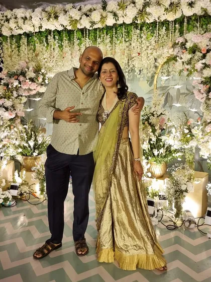 A lovely photo with my husband against a beautiful floral backdrop. I'm wearing a repurposed wedding outfit, combining my Sabya blouse and dupatta with a custom sharara.