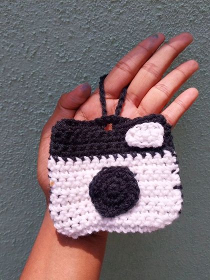 A still shot of the handmade crochet camera charm pouch. It's a fun and functional piece for anyone who loves photography or just wants a unique accessory.