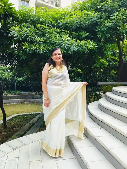 A full look of the client in her beautiful white Kasavu saree, paired with the custom purple blouse and traditional gold jewelry.