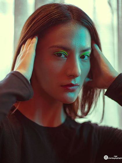 A tight close-up focusing on the neon green makeup and the dual-tone lighting effect on the model's face.
