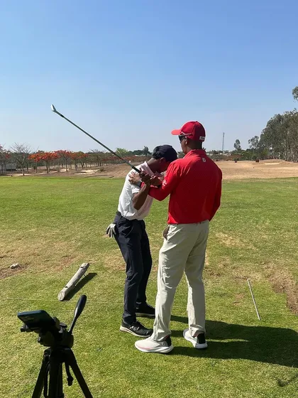A coach provides hands-on instruction to a player. This direct feedback is crucial for building the correct swing mechanics.