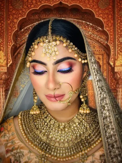 A fusion bridal look that blends tradition with a touch of modern color. The soft blue on the eyelid adds an unexpected yet beautiful element to the warm, neutral tones of the overall makeup.