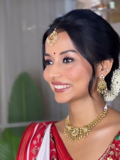 A happy bride is the most beautiful bride. Here, her hair is styled in a neat, traditional bun with a fresh gajra, allowing her beautiful smile and stunning jewelry to shine.