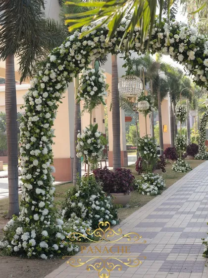 A side view of the lush floral arch, made with hundreds of white chrysanthemums and roses.