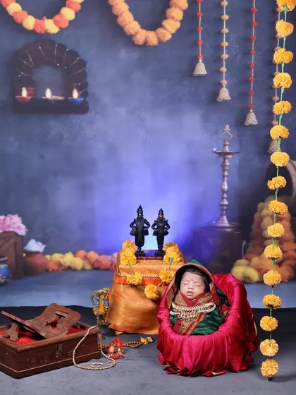 A wider view of the newborn in a Vitthal-Rakhumai themed shoot, sleeping peacefully in a pink bassinet against a devotional backdrop.