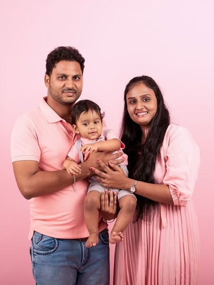 A lovely family portrait against a solid pink background. Coordinated outfits can make your family photos look polished and cohesive.
