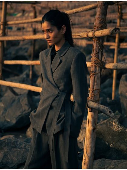Using the rustic texture of a bamboo structure, this shot adds a raw, natural element to the fashion story. The warm light enhances the mood.