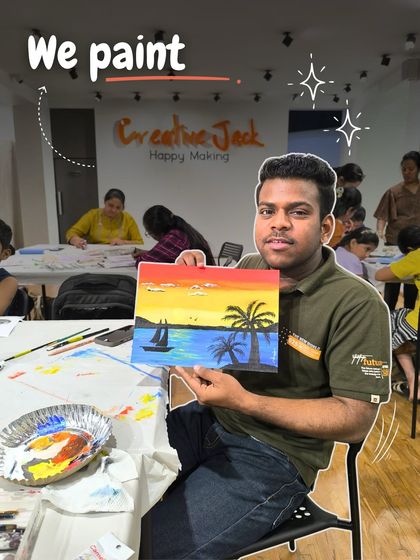 A young man shows off his tropical sunset painting, complete with a sailboat and palm trees, which he made during a guided workshop.