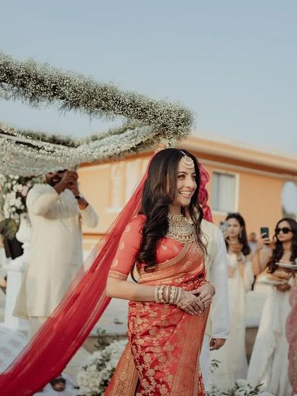 A beautiful bride walking under a delicate phoolon ki chadar made of baby's breath.